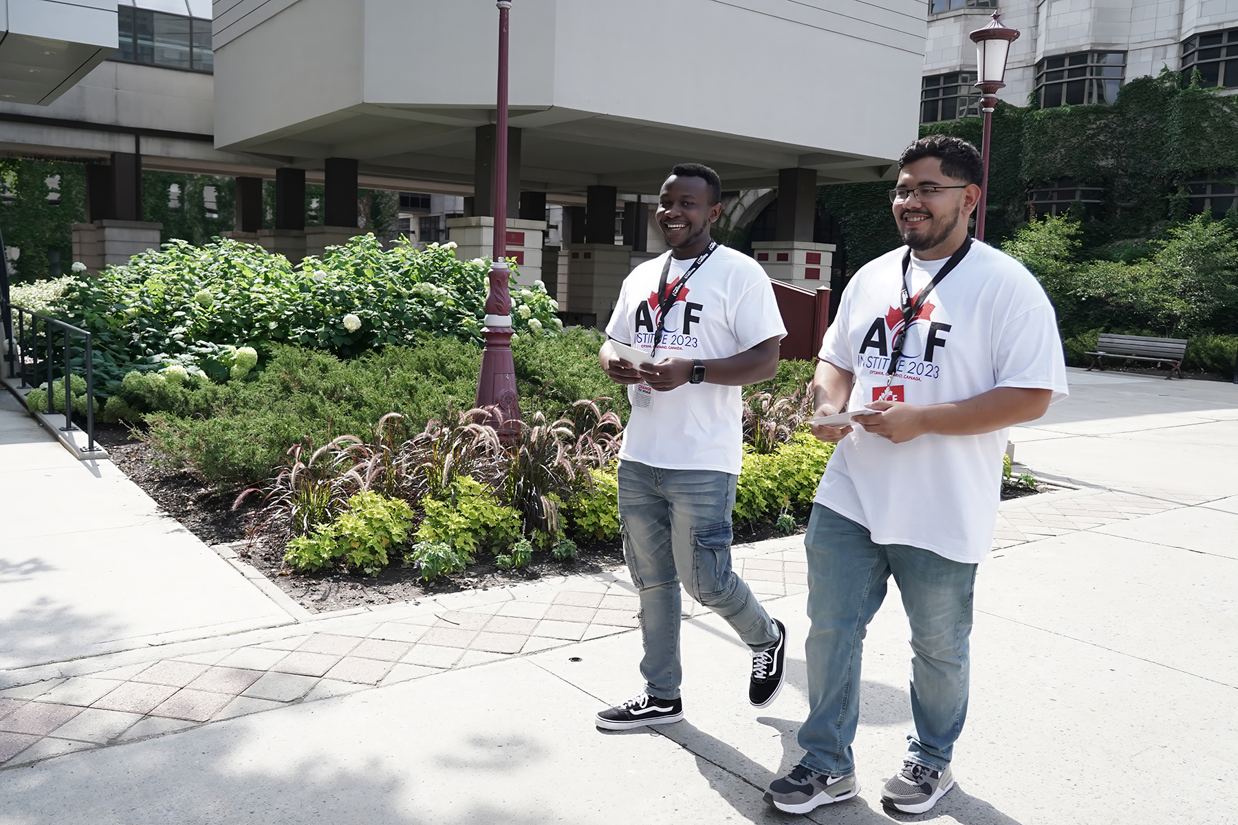 Two young men, one black, one Hispanic, wearing matching white tshirts and jeans.