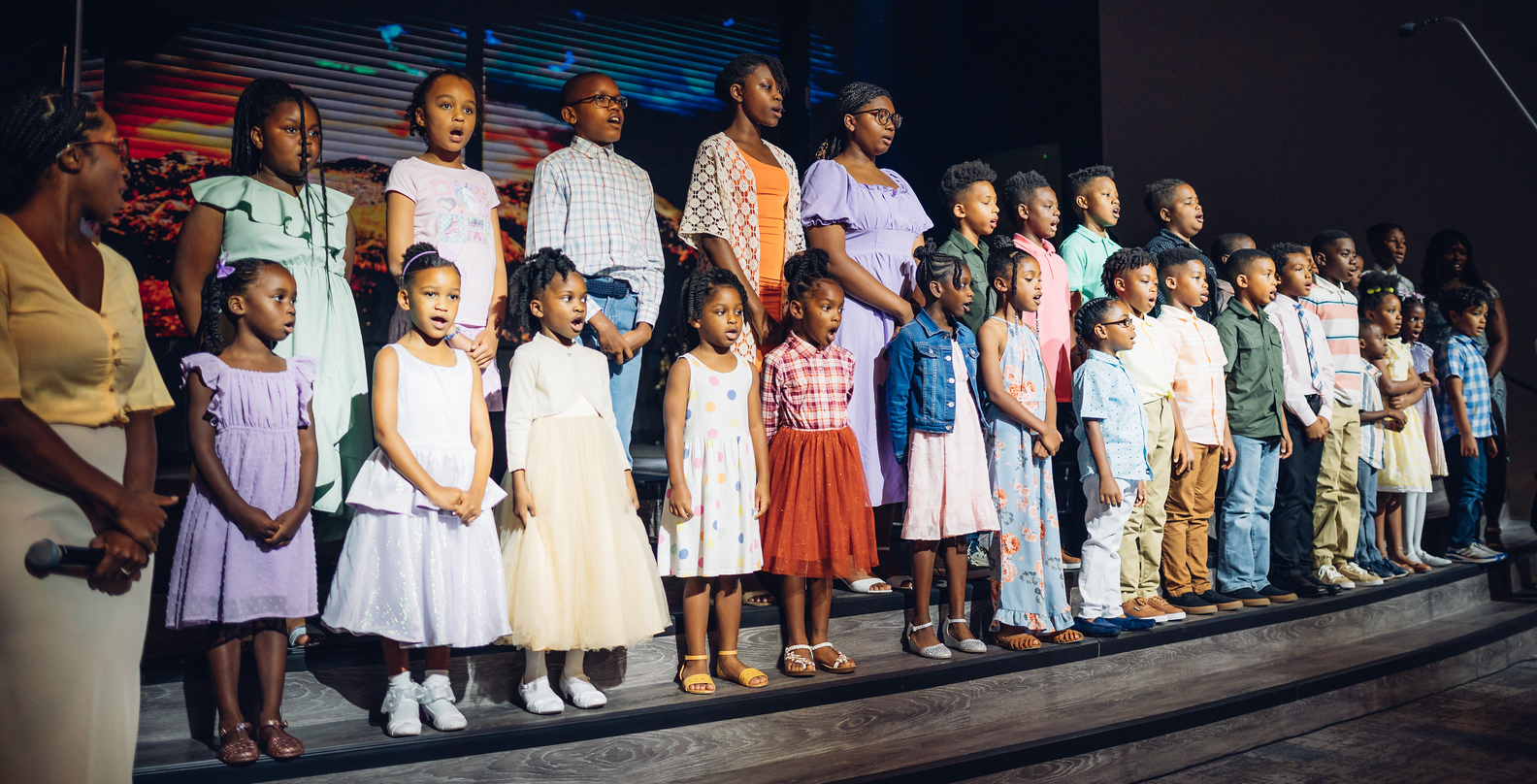 Several black children singing on stage in a choir