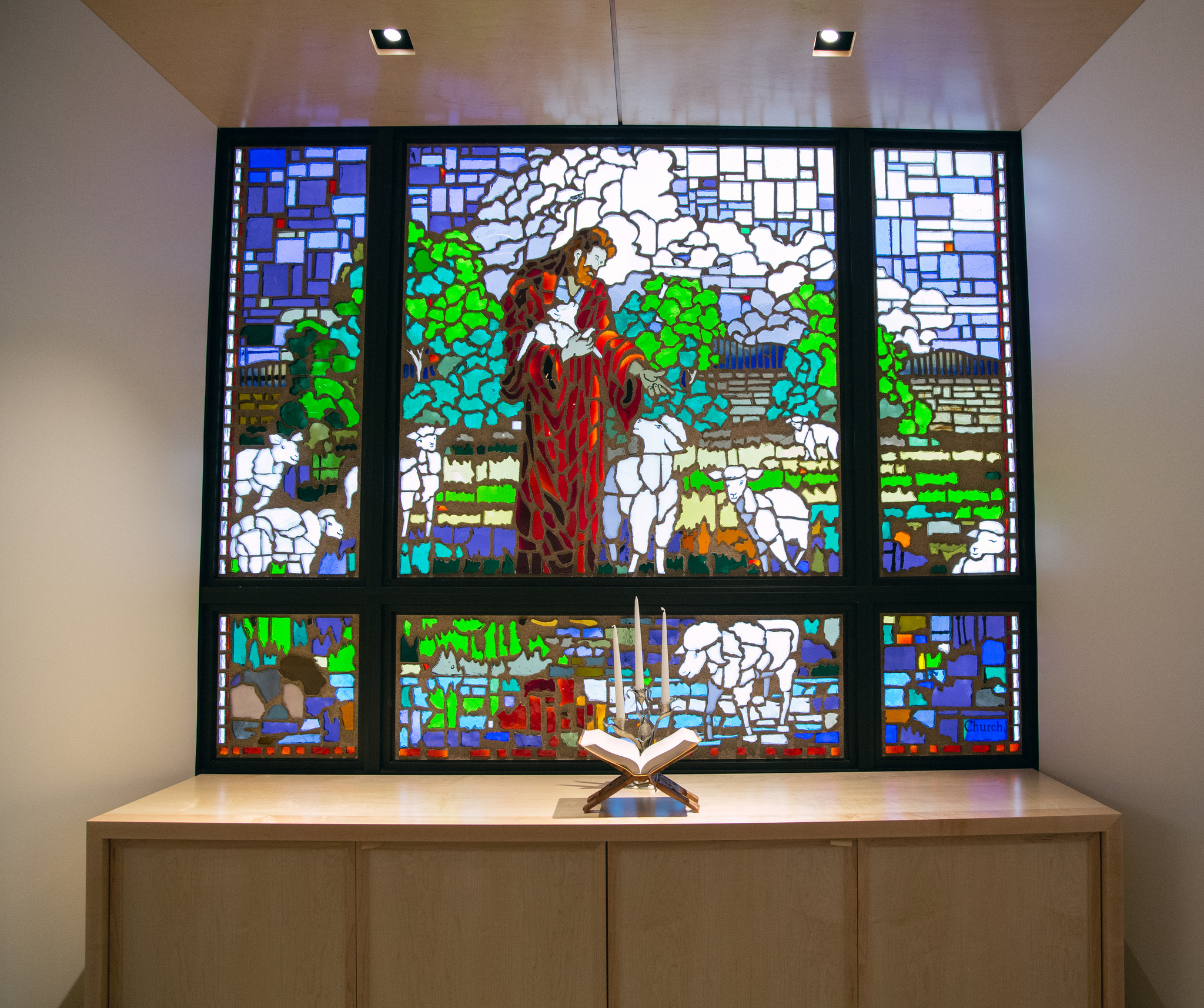 The stained-glassed was created by Clayton Connolly. The glass portrays Jesus as the good shepherd. Jesus is surrounded by nine sheep, representing the division’s nine union.