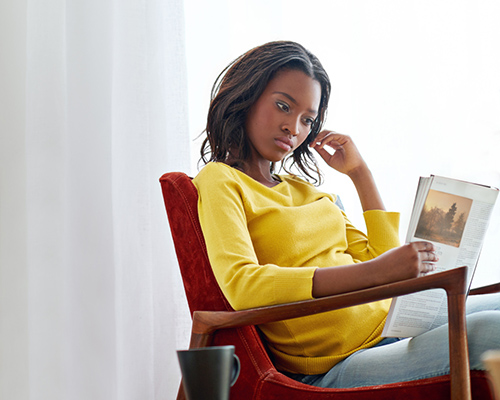 African American woman reading magazine stock photo