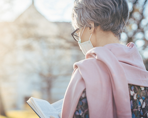 woman wearing mask and reading a Bible