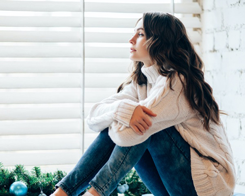 Young woman gazing wistfully out window