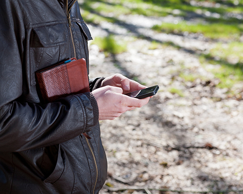 stock photo of man on phone outdoors with bible under arm