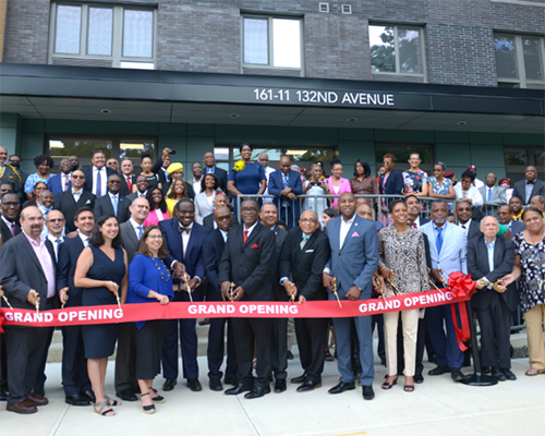 Large crowd with leaders cutting a ribbon outside of a building