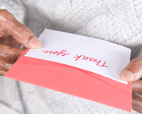 stock photo of elderly woman holding thank you card