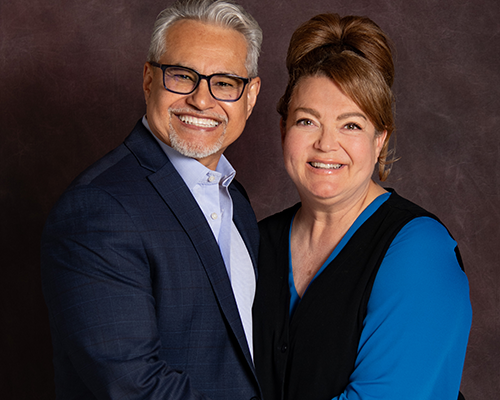 Hispanic couple pose for a formal photo with arms around each other