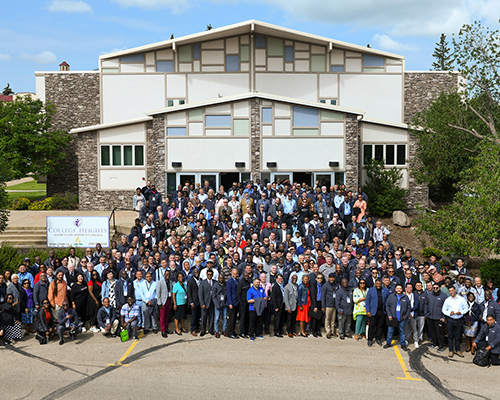 Photo of several people standing in front of a building smiling