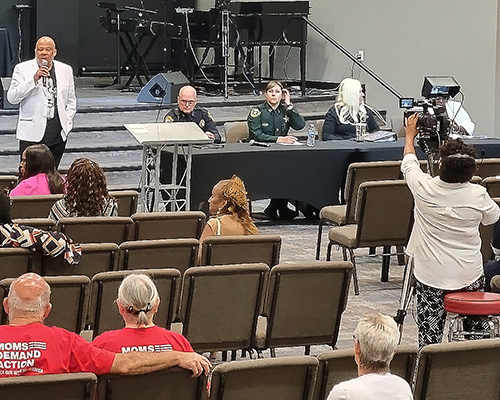 Black man standing in front of people in an auditorium, speaking