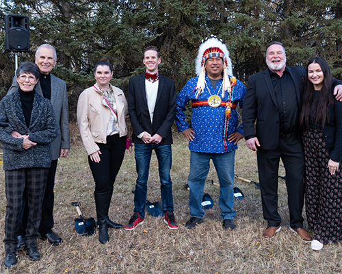 A group of people standing on a patch of grass, including an Indigenous chief in uniform