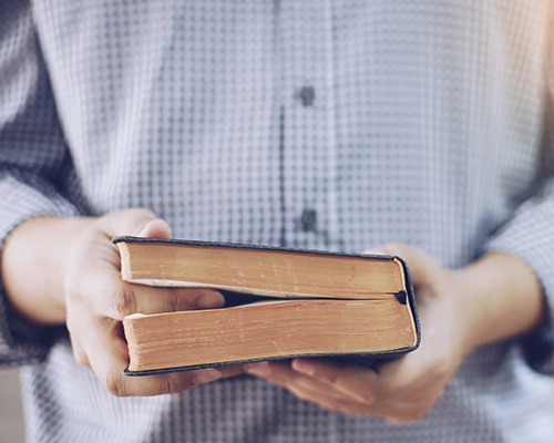 stock photo of man holding Bible with finger inserted in text