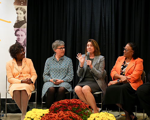 A panel of women, two black and two white, speak to an unseen audience