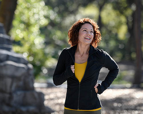 Smiling white woman jogging outside.