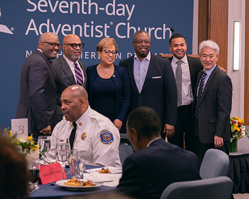 Photo of a diverse group of people taking a photo at the front of a conference room