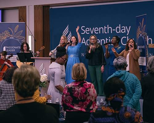 A praise team singing on a stage in front of a crowd.