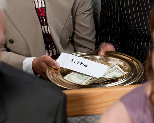 Stock photo of tithe in offering plate going down church pew