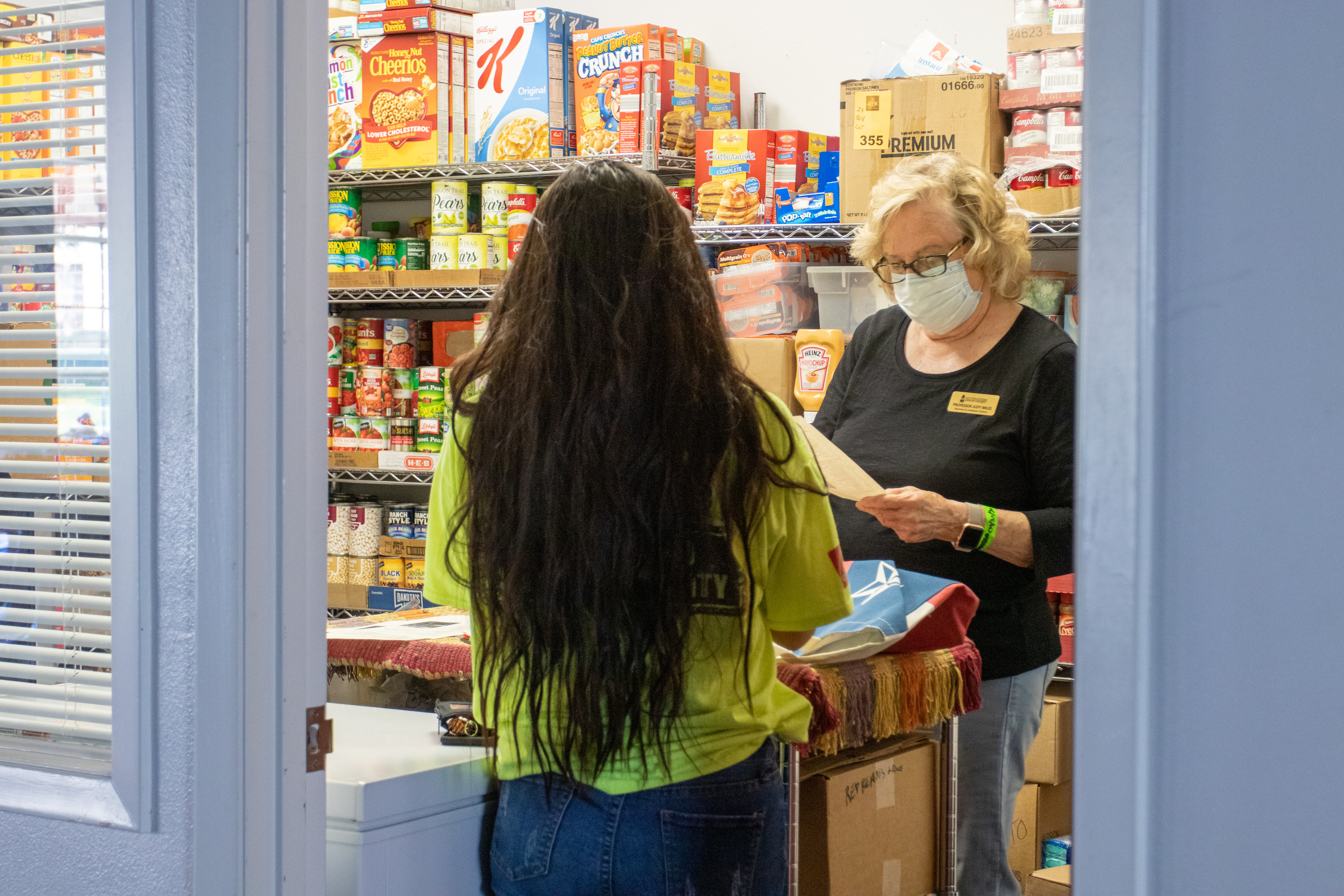 Young student talking to older woman standing in a food pantry