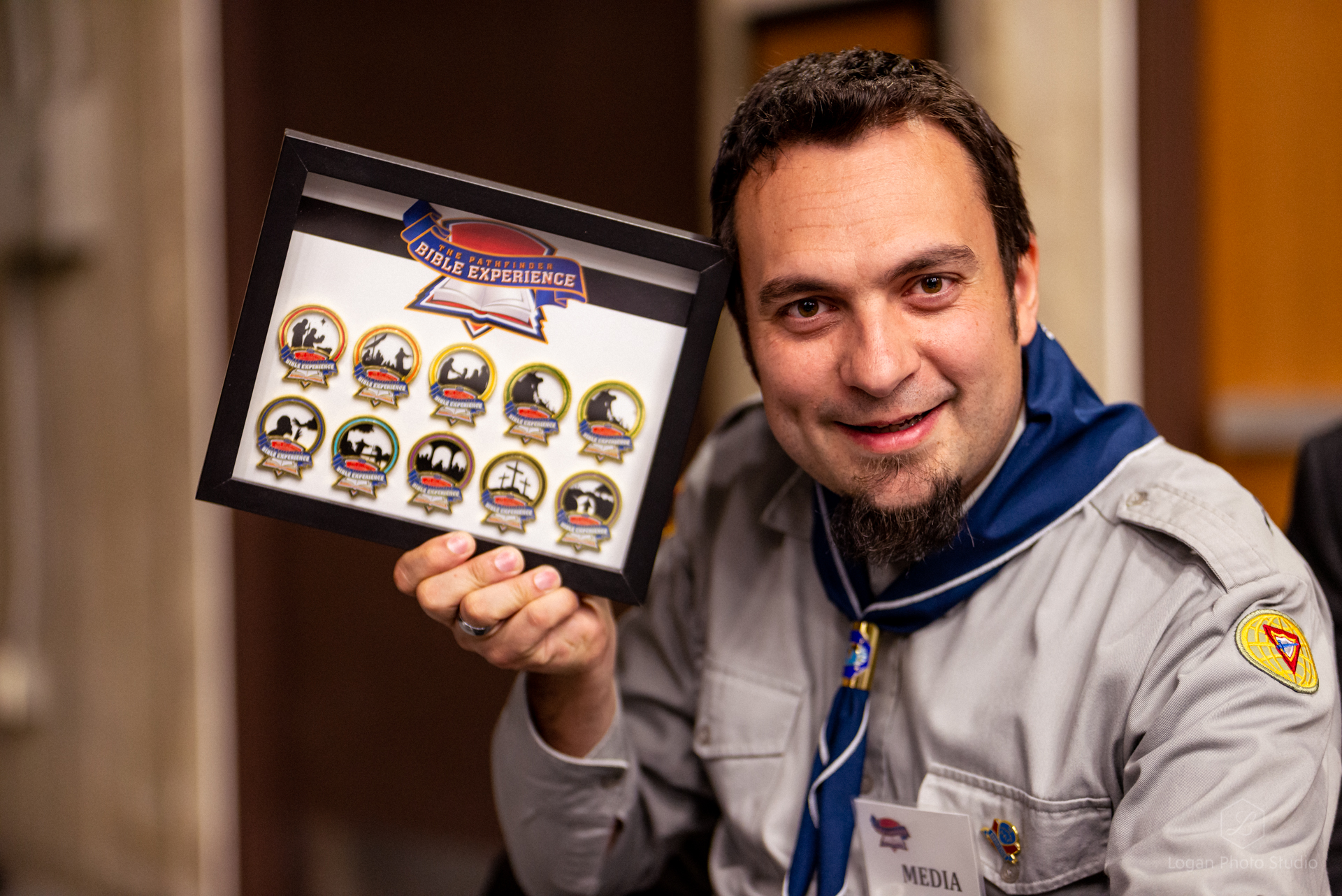 Youth director of the British Union Conference, Dejan Stojkovic, poses with pins from previous PBE events. 