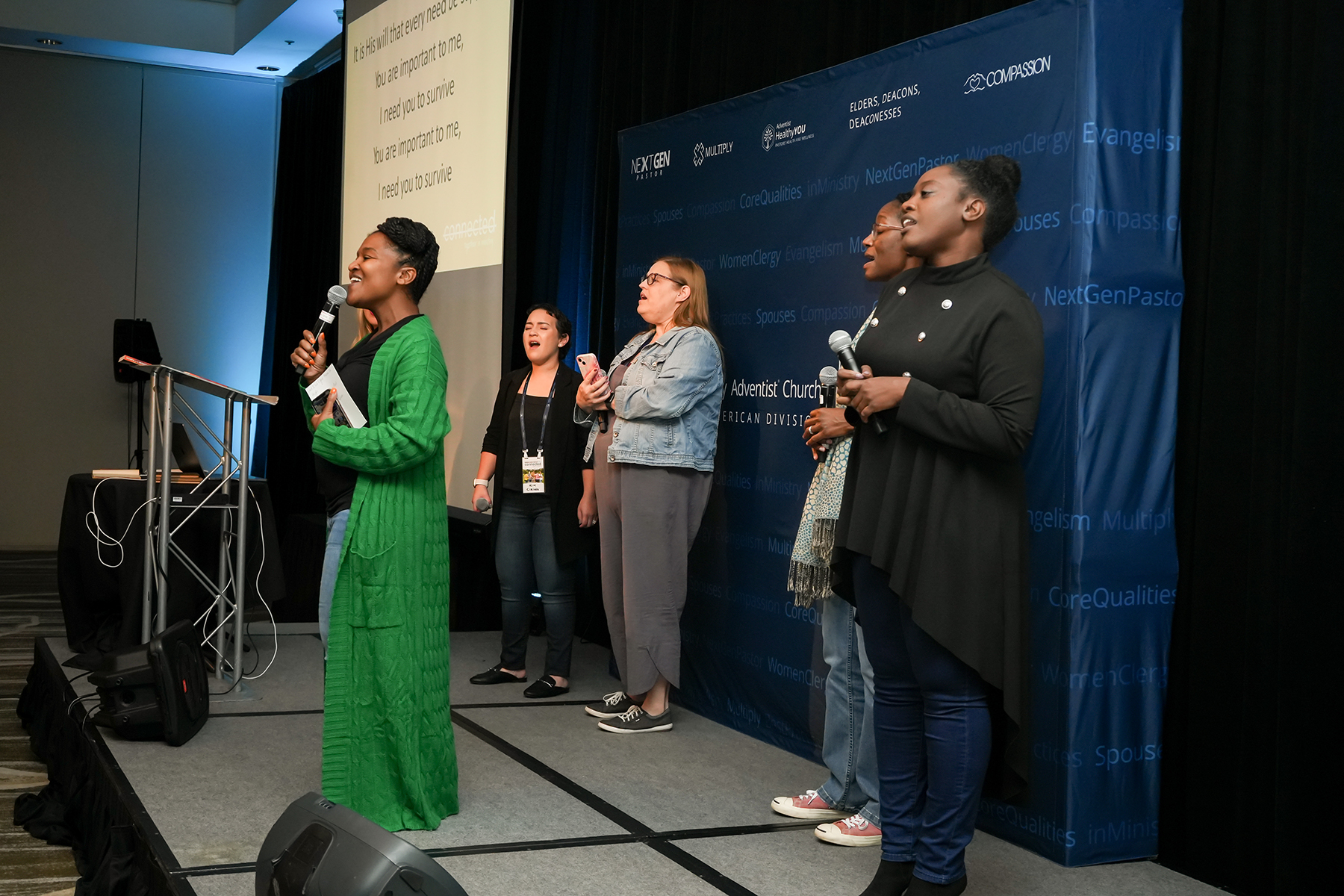 Women of different ethnicities singing together on stage. 