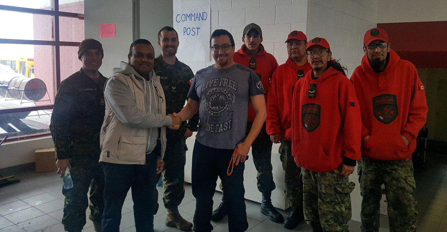 Daniel Saugh, Canadian Programs Manager for ADRA Canada shakes hands with the Band Councillor Gary Kam, pictured here with some Canadian Rangers who were also activated as part of the emergency response.