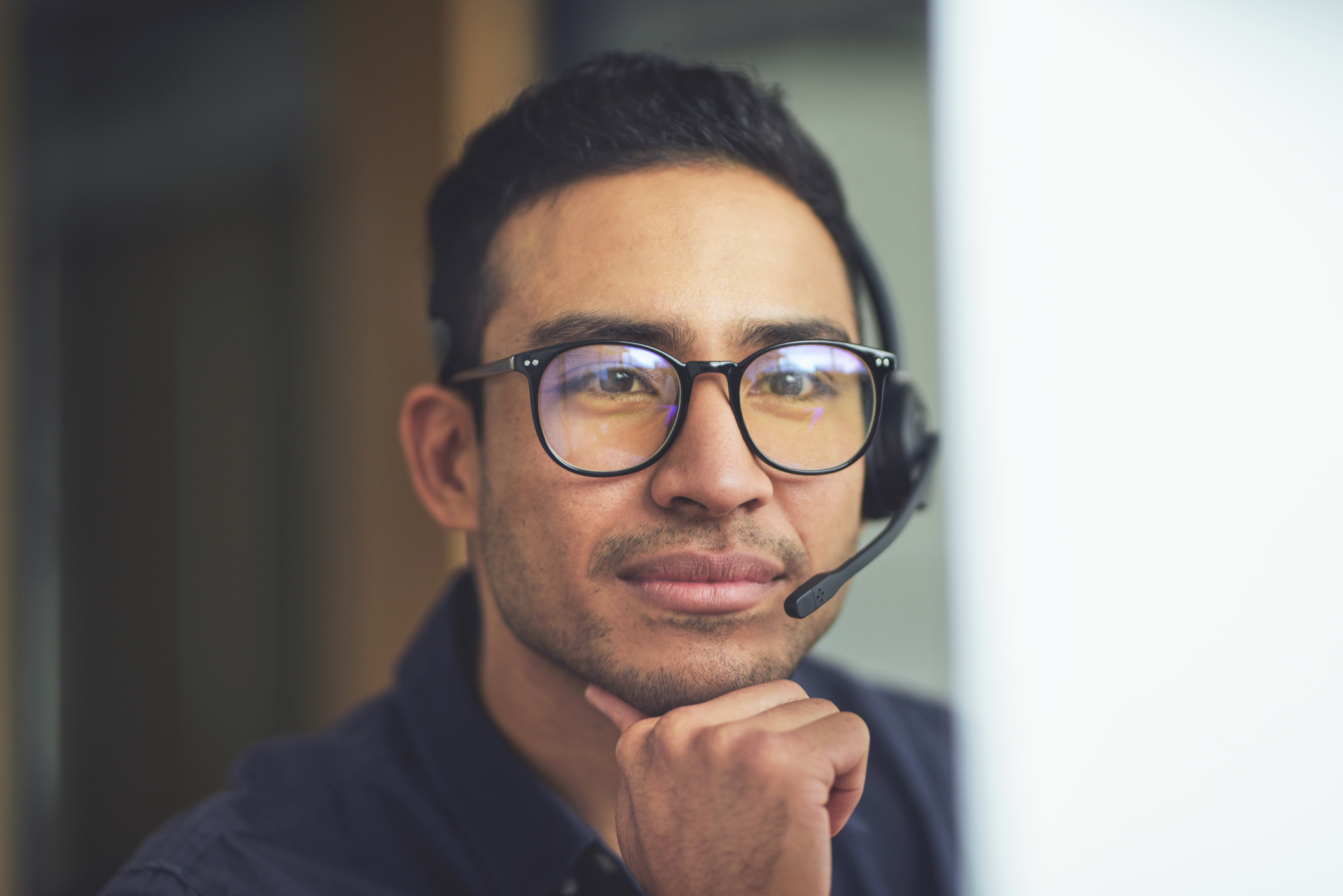 Asian man wearing a microphone/headphone headset.