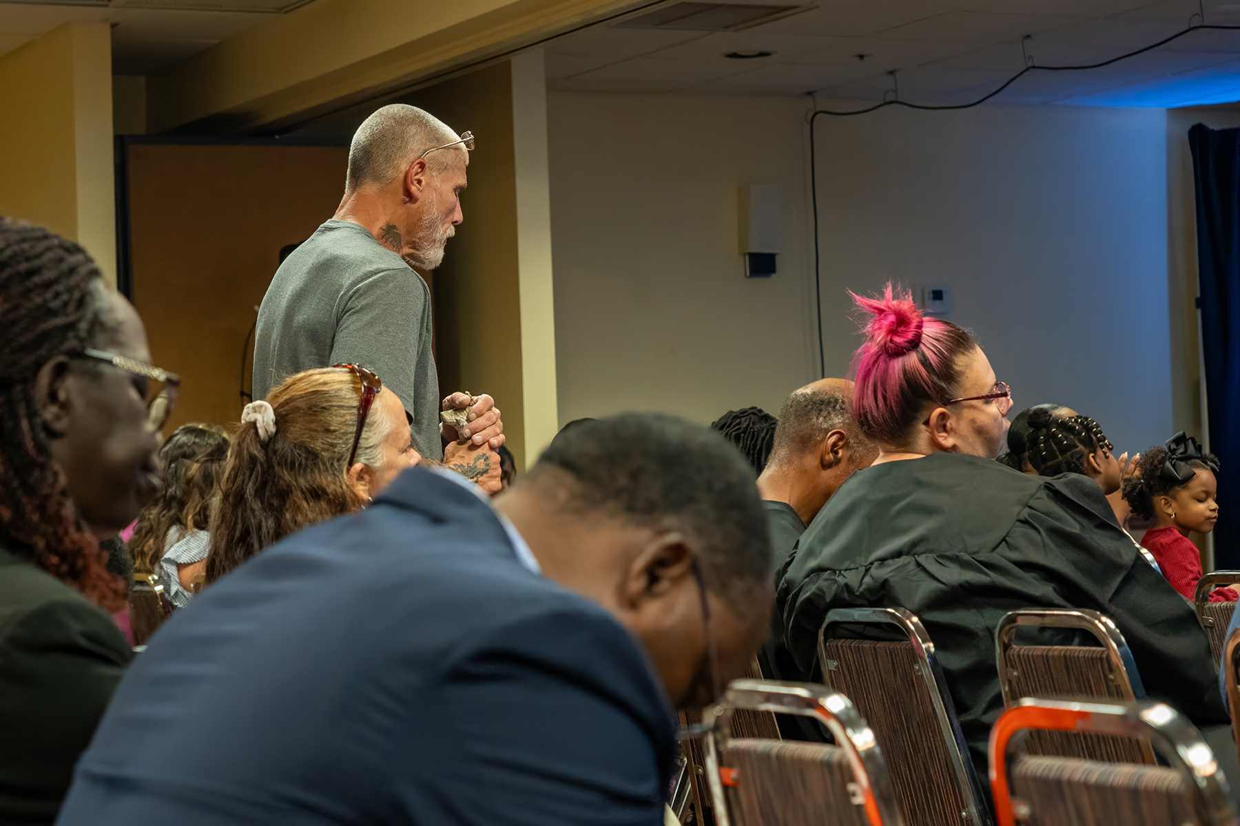 A white man standing up in a room full of people