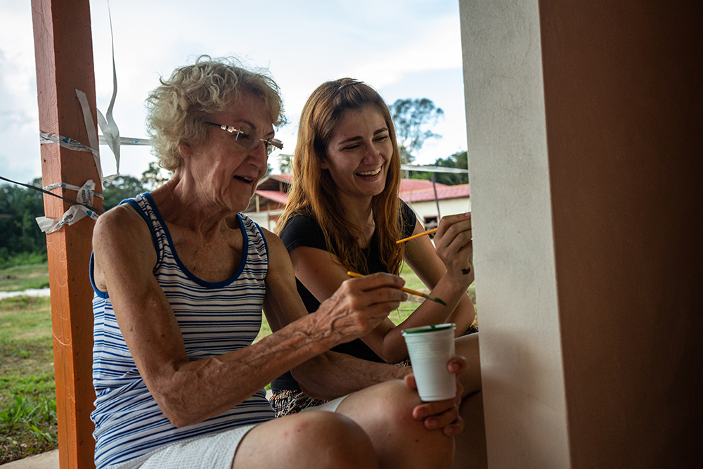 Elaine Halenz (L), retired missionary from the U.S., paints alongside Pollyani Mamedes (R), an art student from Brazil. 