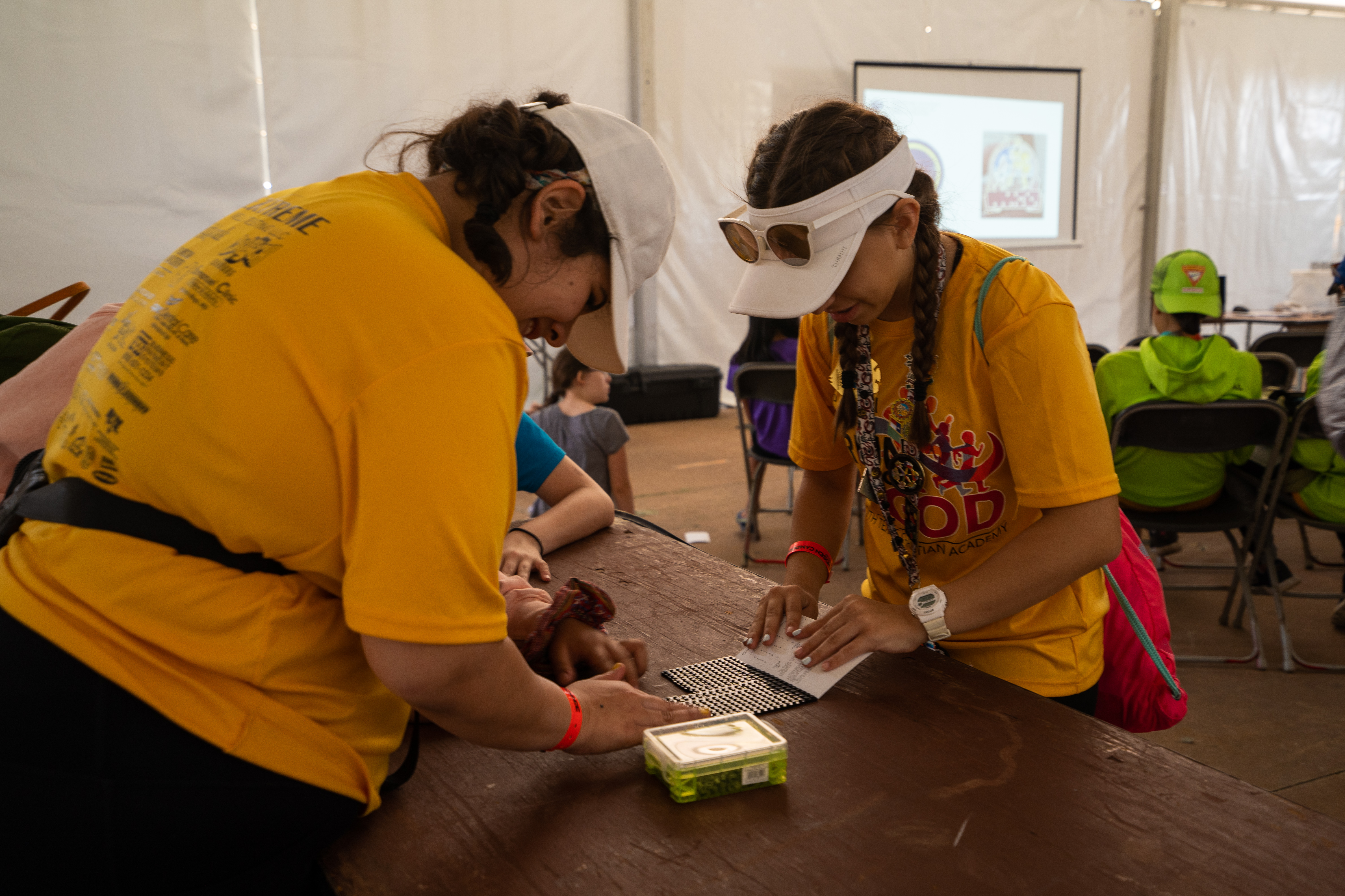 Two pathfinders organize Legos during an activity where they use the pieces to construct their names in braille. 