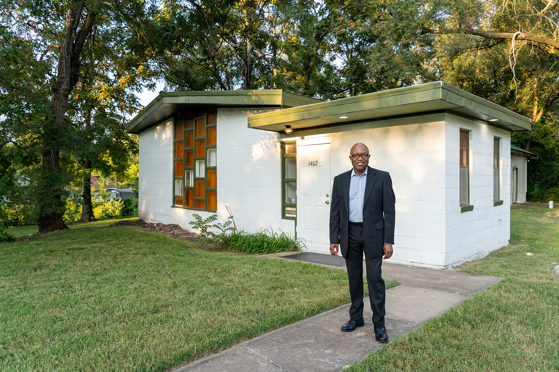 Black man standing in front of a very small church building