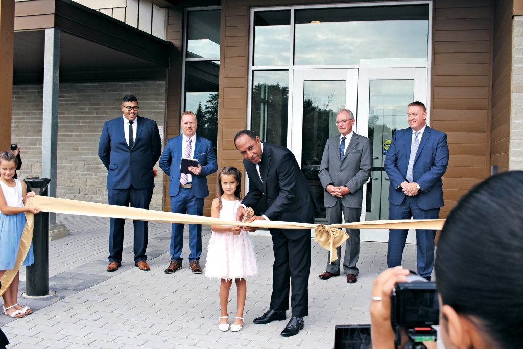 Mansfield Edwards and Eden M. cutting the ribbon, as Really Living youth pastor Benton Lowe; lead pastor, Francis Douville; SDACC president, Mark Johnson; and guest speaker, Dan Linrud look on.