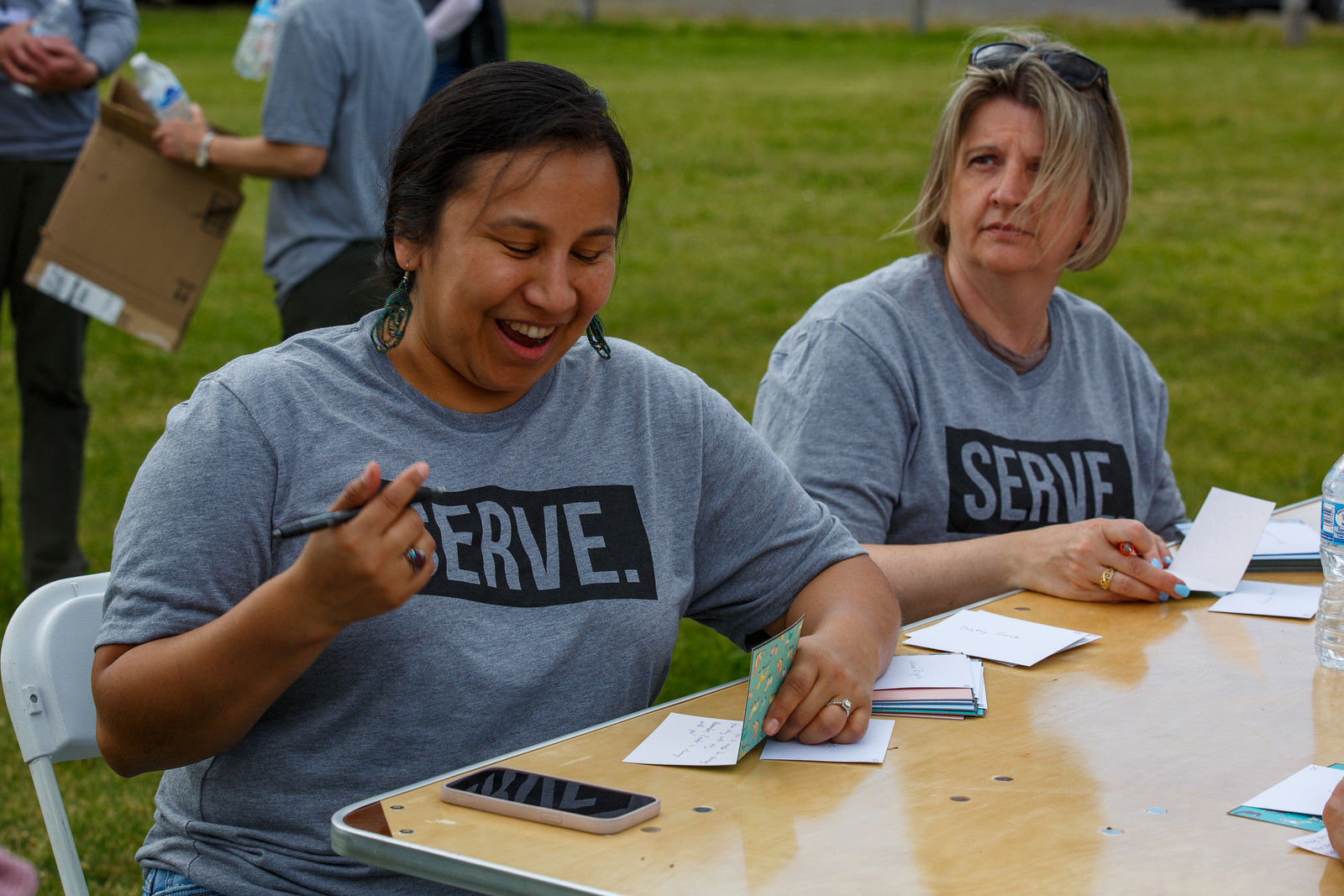 Along with their shoes, children received hand-written cards with colored pencil art. Photo: Candace Jimenez (left), and fellow volunteer Kris Nagele prepare some of the cards.