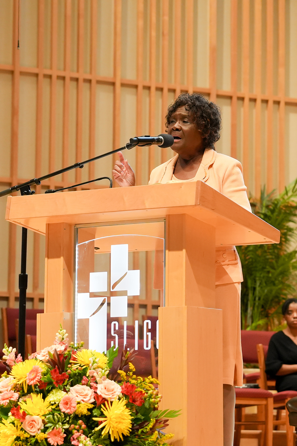 Black woman preaching behind a pulpit in a church. 