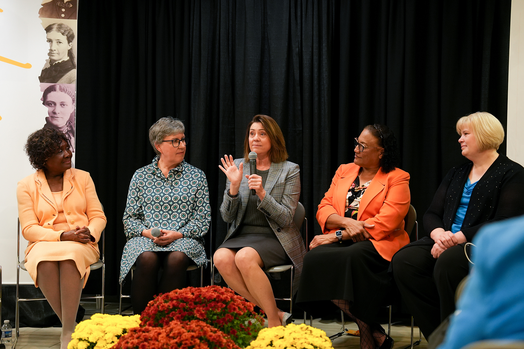 A panel of women, two black and two white, speak to an unseen audience