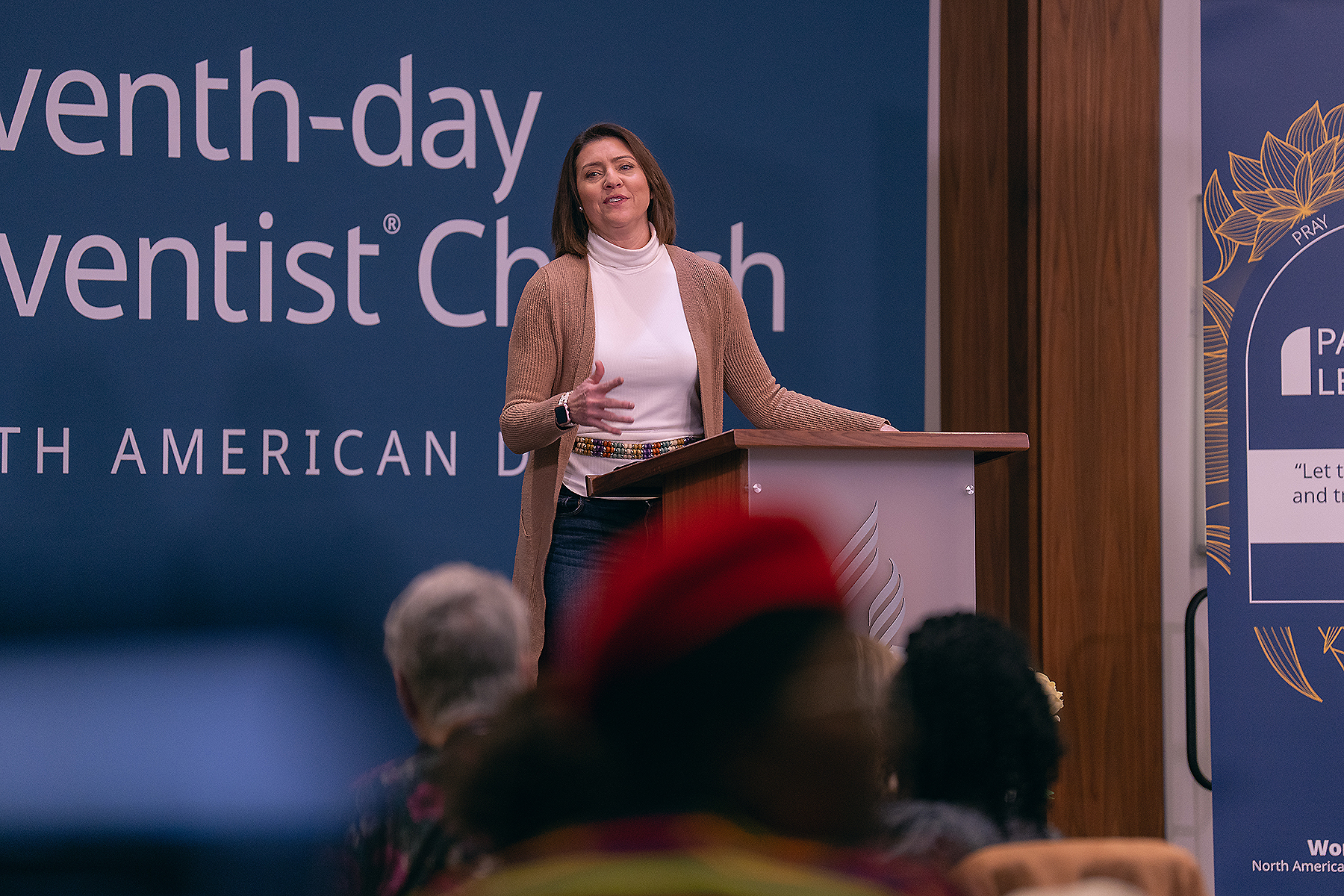 A smiling woman standing in front of a crowd, speaking