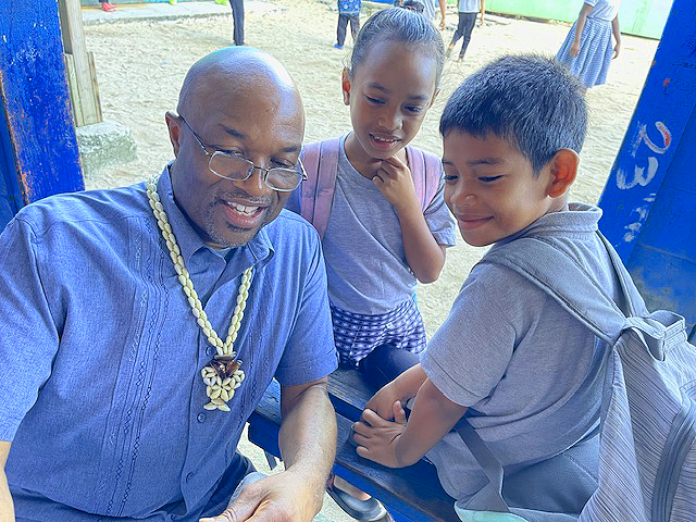 Black man, smiling with brown children