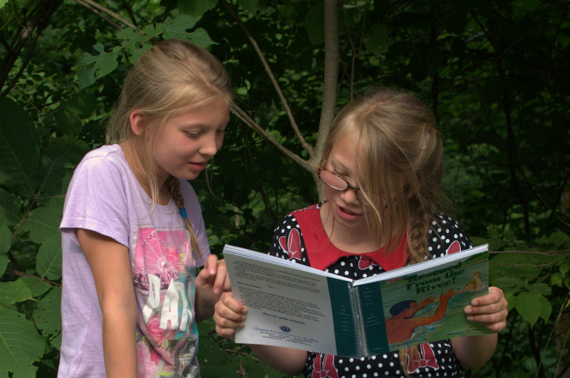 girl reads Braille to her sighted sister