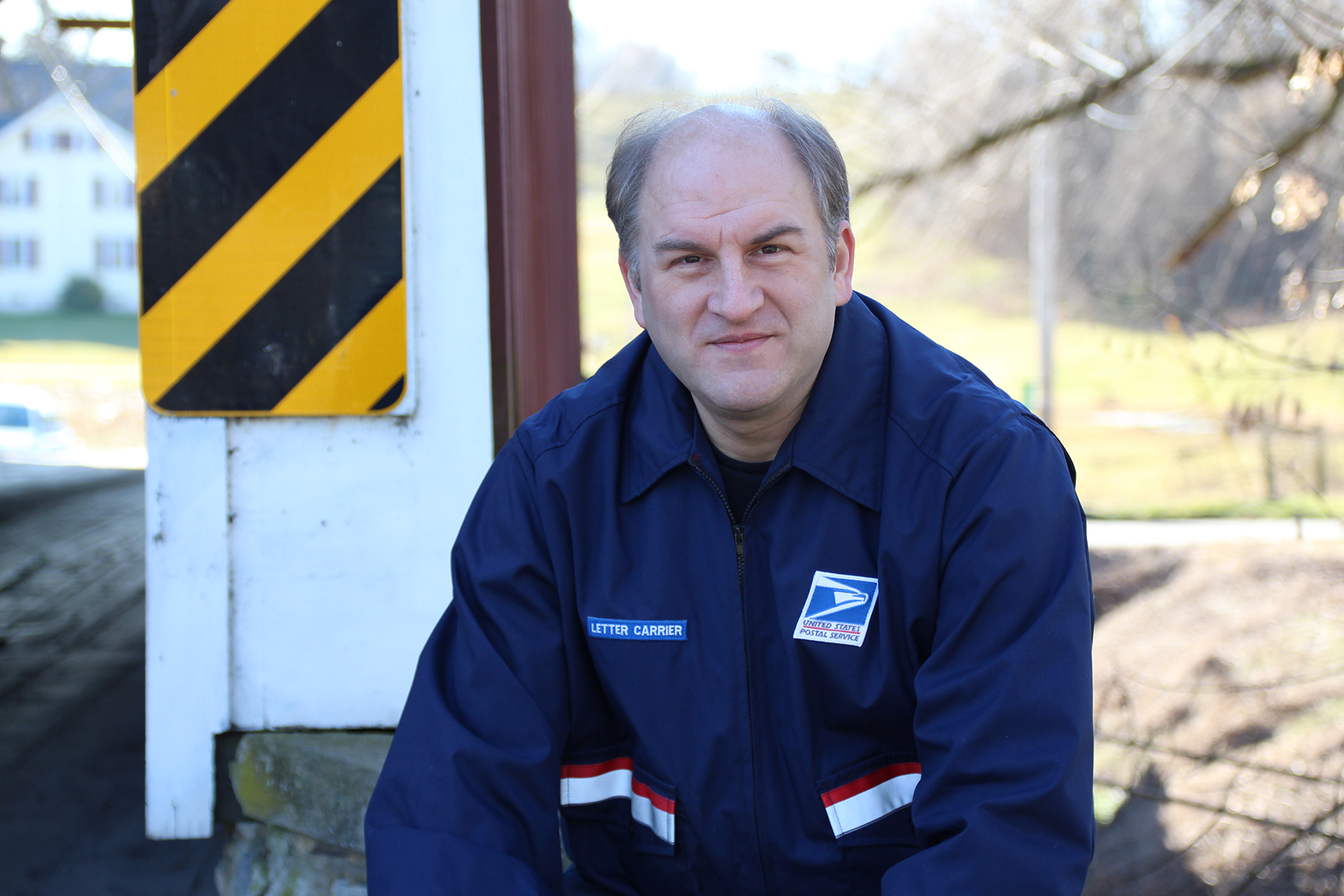 white man with US postal service uniform sitting outside