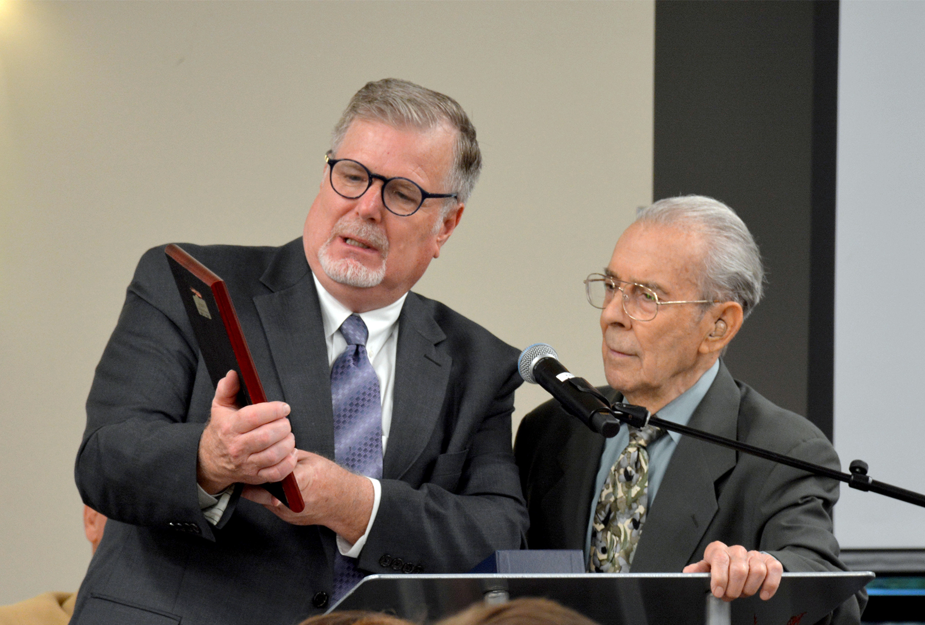 Dale Galusha, president of Pacific Press, reads a commemorative plaque given to Paul Damazo, founder and executive director of the Literature Ministry, for bringing the new Literature Ministry Distribution and Training Center from dream to fulfillment. 