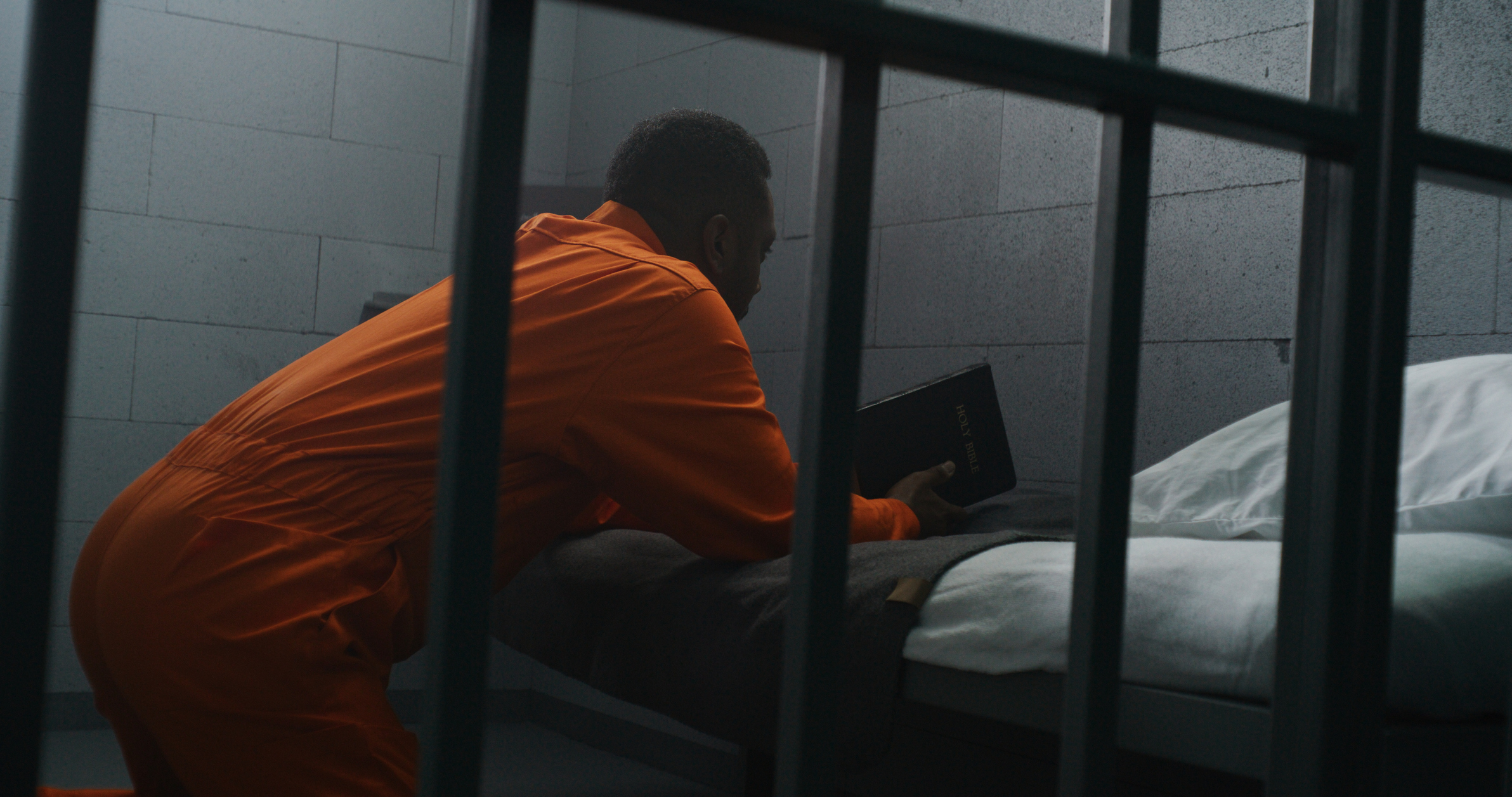 stock photo of African American man reading Bible in prison