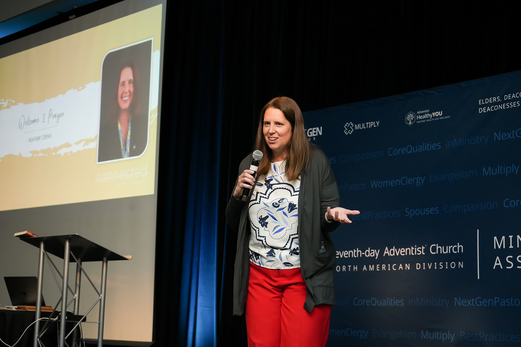 White woman speaking on a stage smiling.