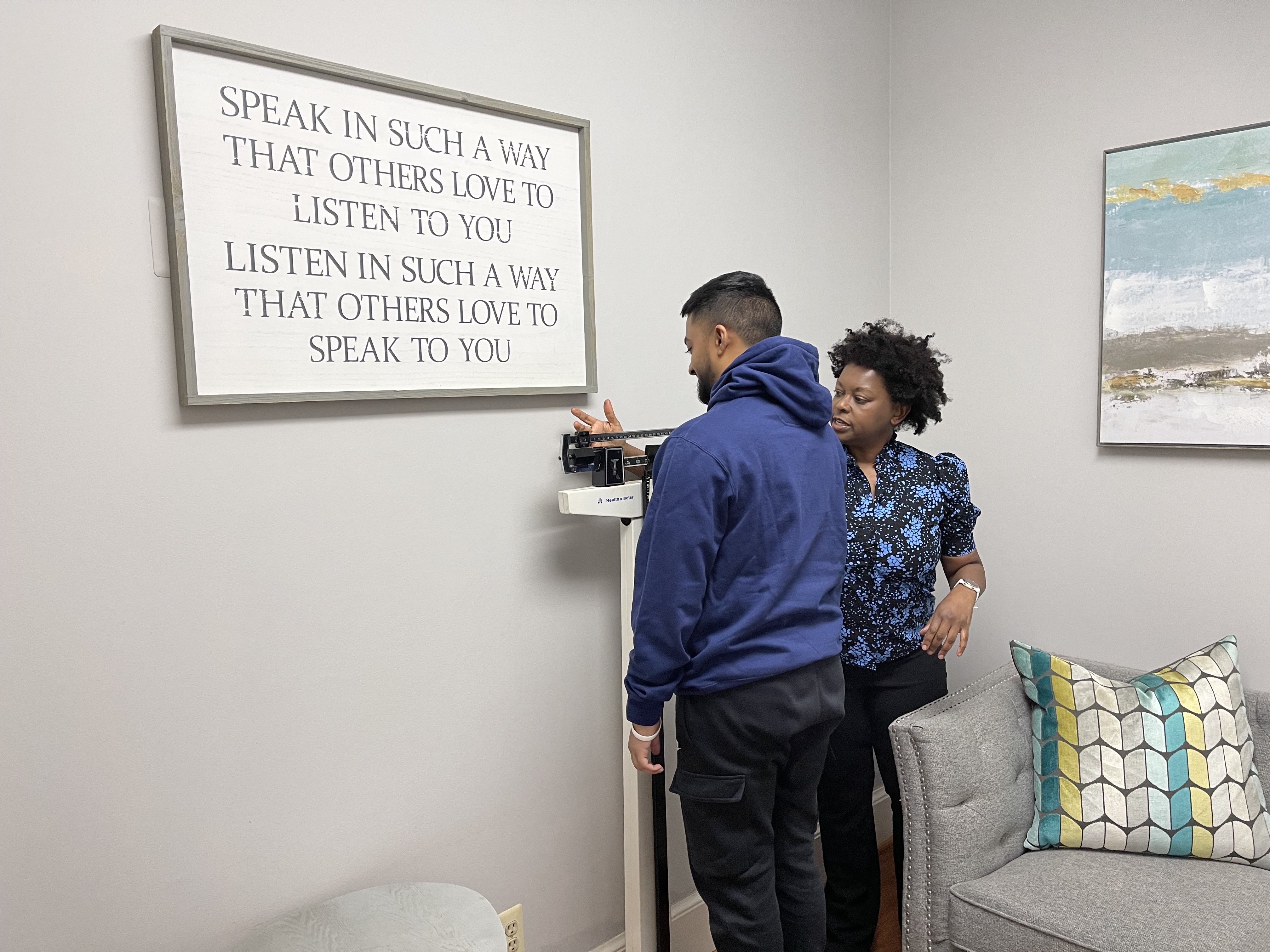 Anelise Antunes, wholistic health coach and nutritionist, serves as the resident health coach for the resource center arm of the Capitol Hill Counseling and Resource Center; here, she's weighing a male client.