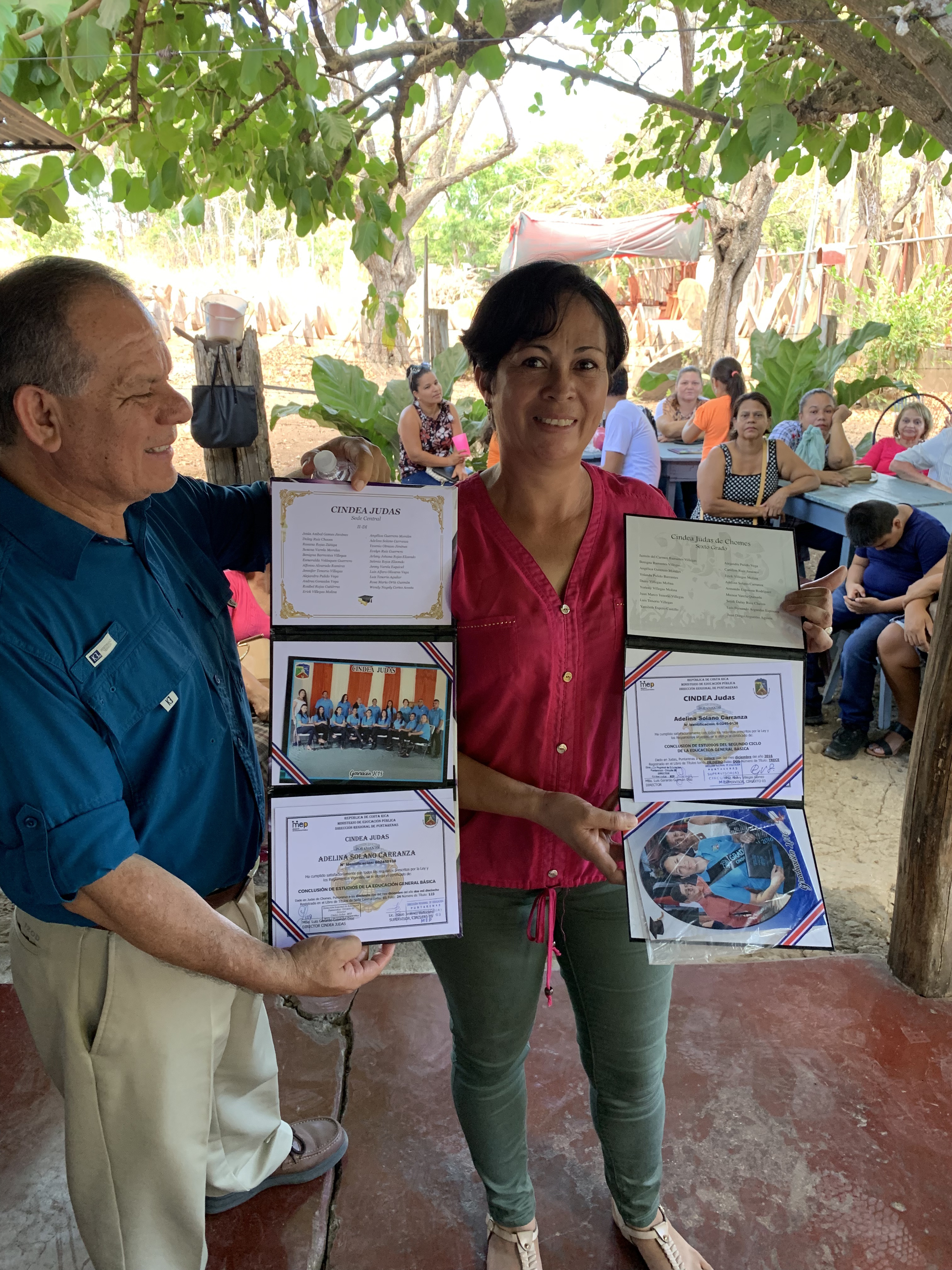 In March 2019, Partners in Mission held an alumni reunion for those who completed the program successfully. This woman (right), with the help of David Poloche, ADRA director for the IAD, shows her elementary and secondary school degrees she earned after completing the Partners in Mission program.