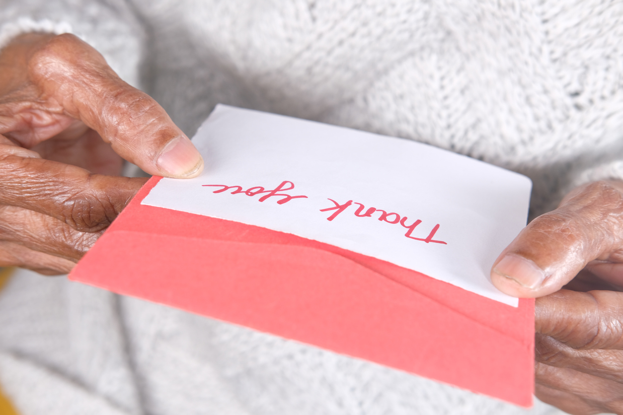 stock photo of elderly woman holding thank you note