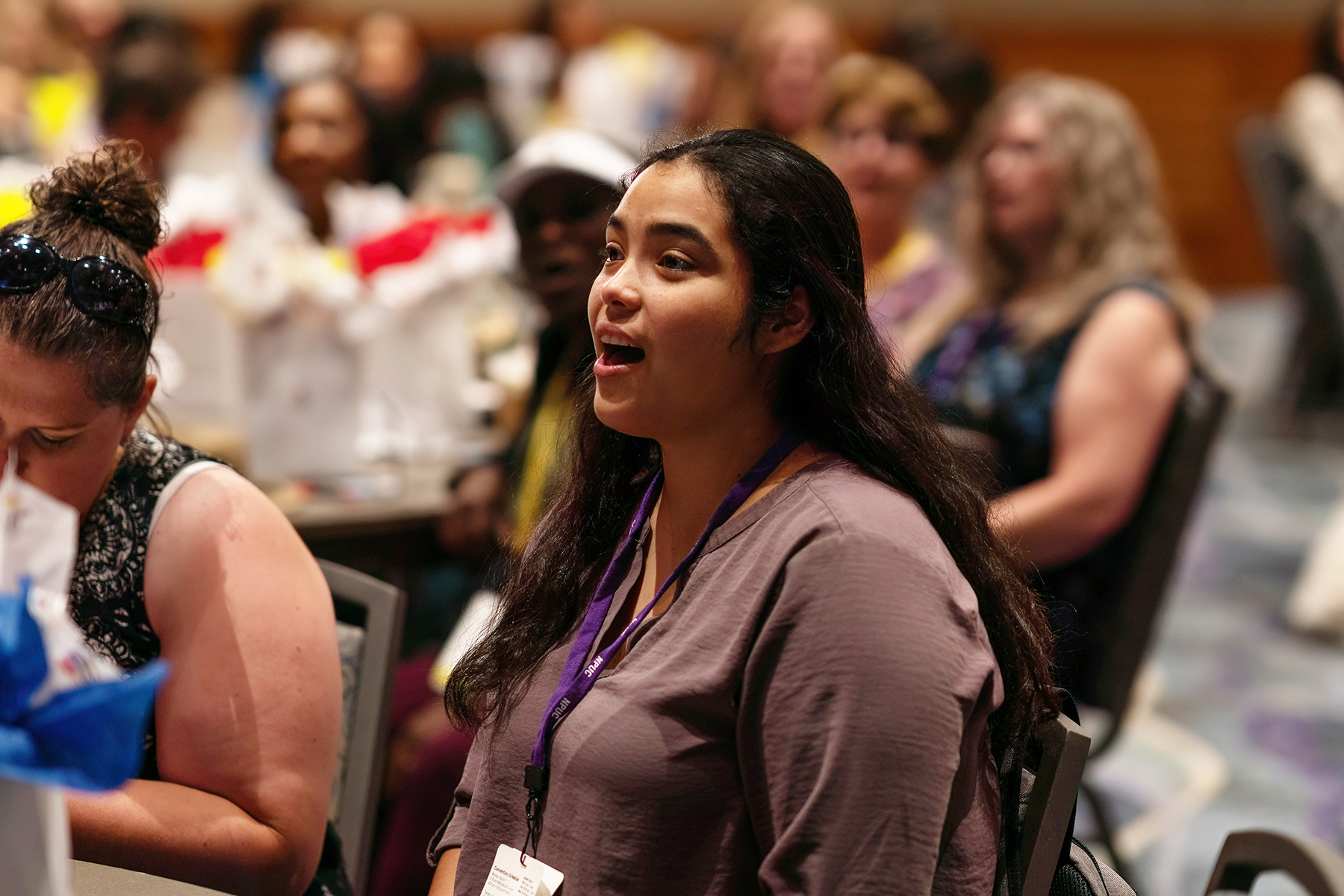 Hispanic woman singing in a blurred crowd