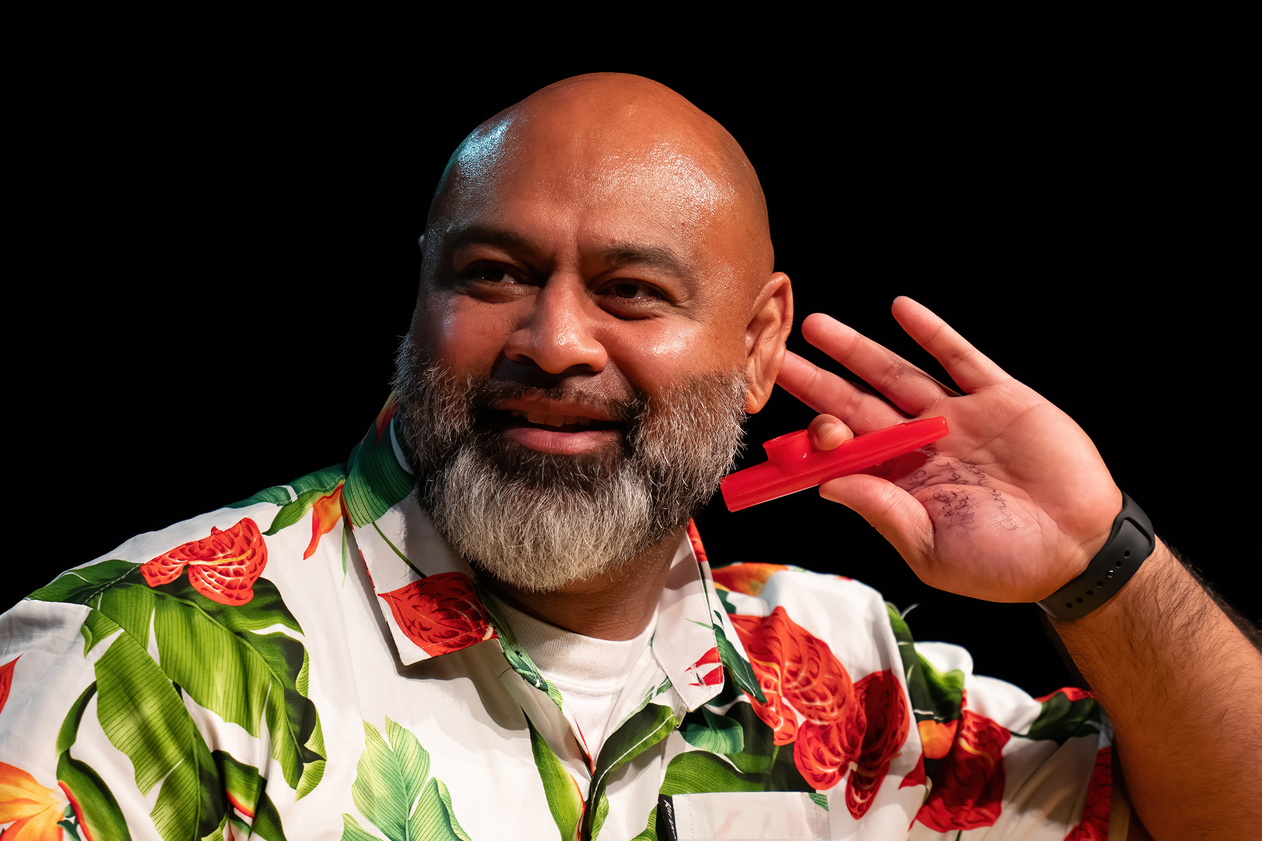 Close-up of a smiling Samoan man with a kazoo in hand 