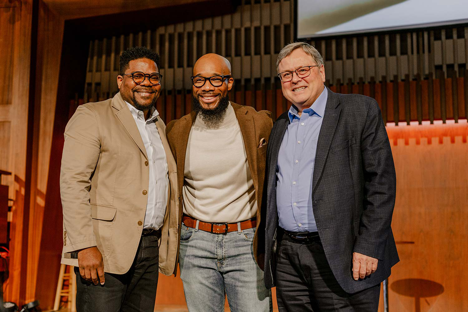 Three men, two black and one white, pose for a picture in a church setting.