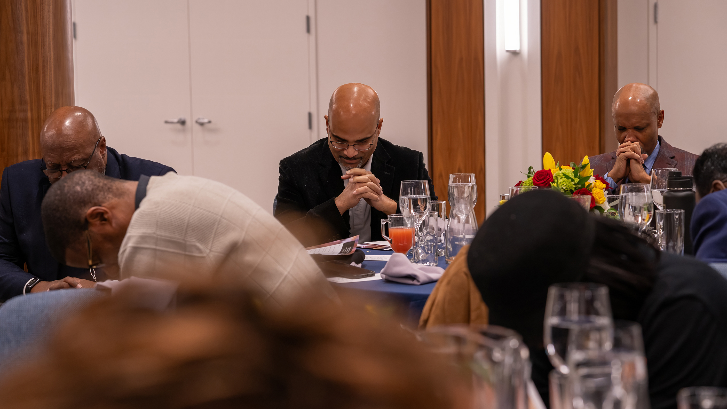 Black men praying at a table