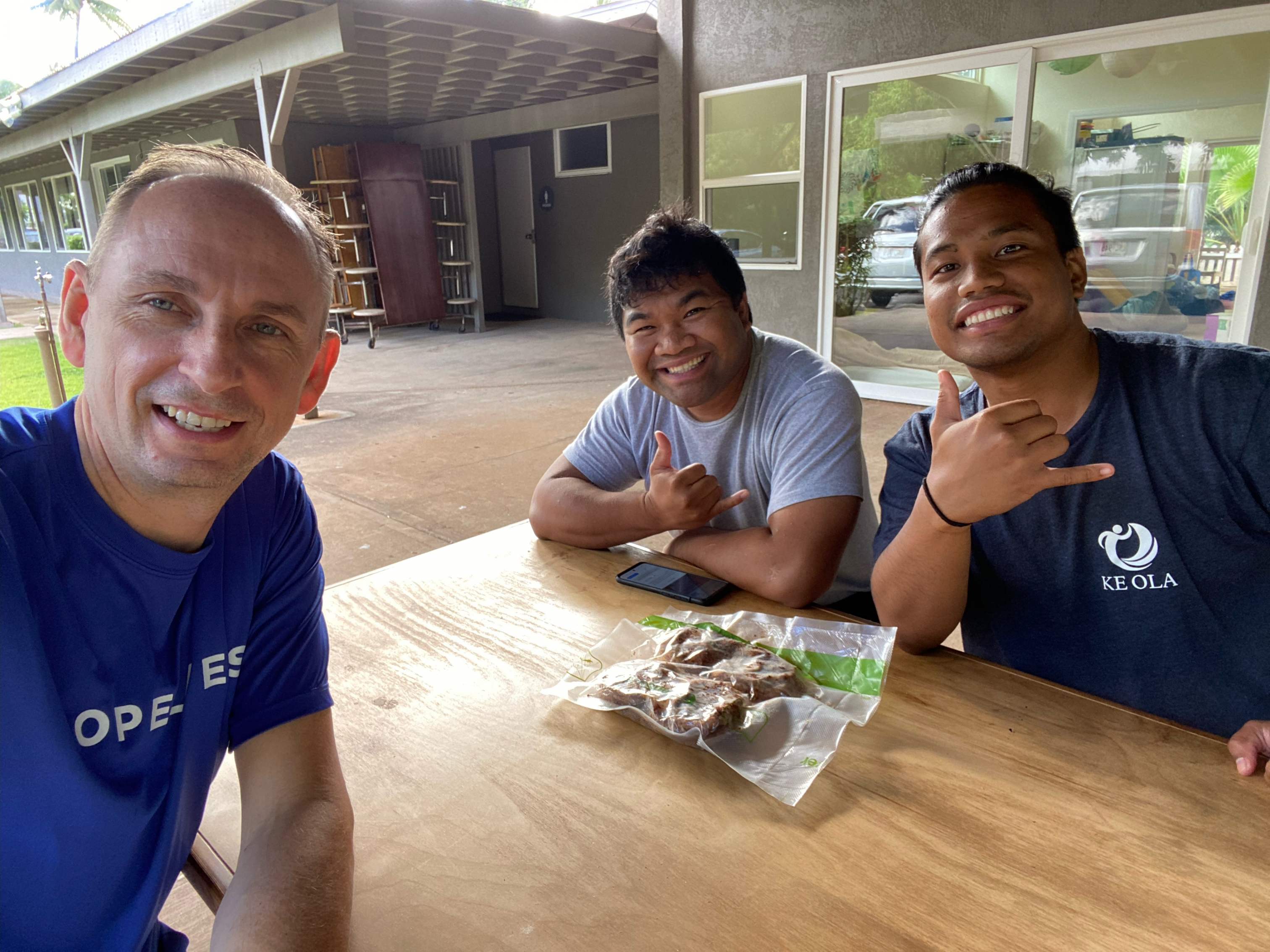 Photo of three men seated and smiling, one white and two of Hawaiian descent