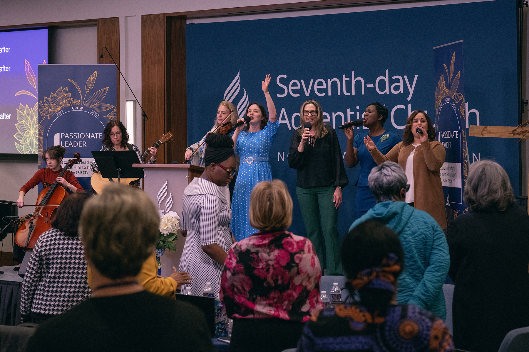 Praise team singing on a stage in front of a crowd.