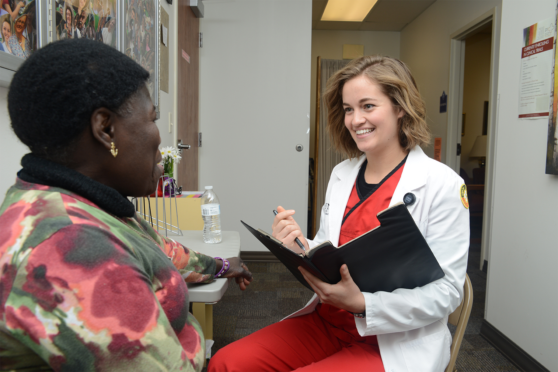 A health care worker in a white coat speaking to another woman