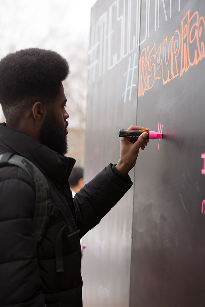 Attendees at the Solidarity Wall, erected outside of the Campus Center for people to write messages of empowerment and support, photo credit Jessica Condon